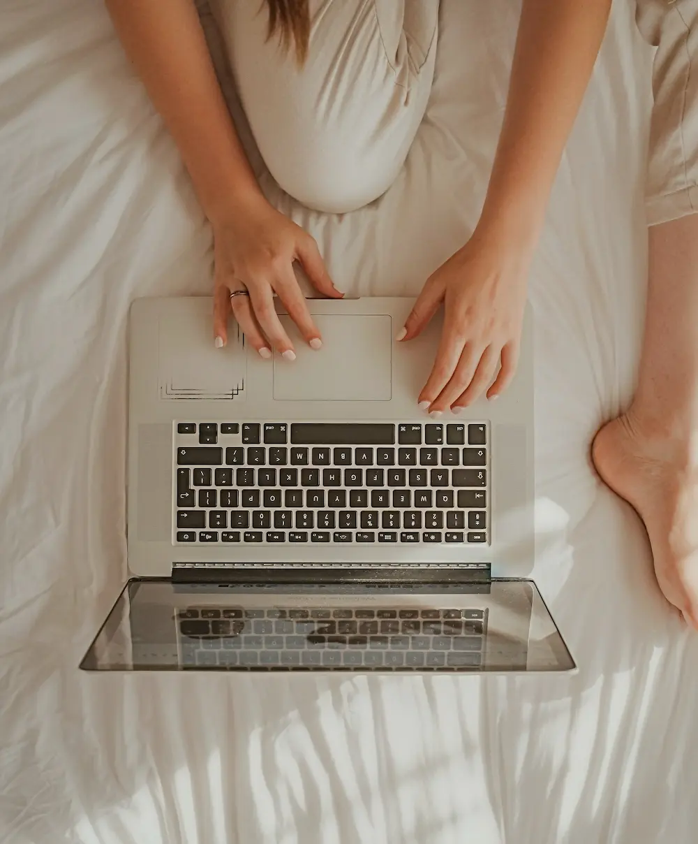 Top-down shot of Monique on her laptop on a bed